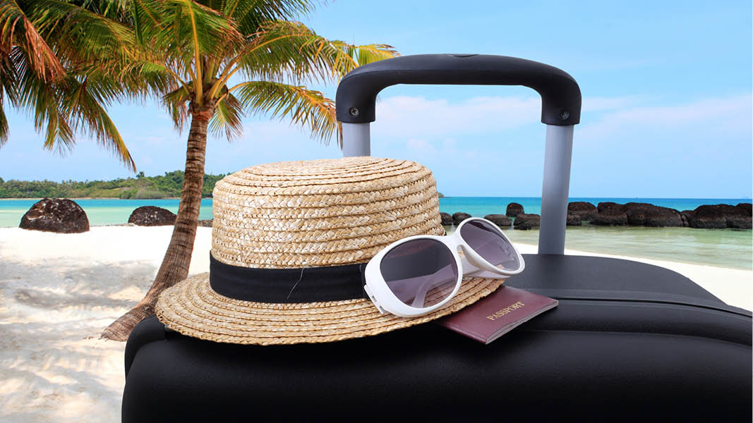 Solhatt, solglasögon, pass och resväska på semestern.